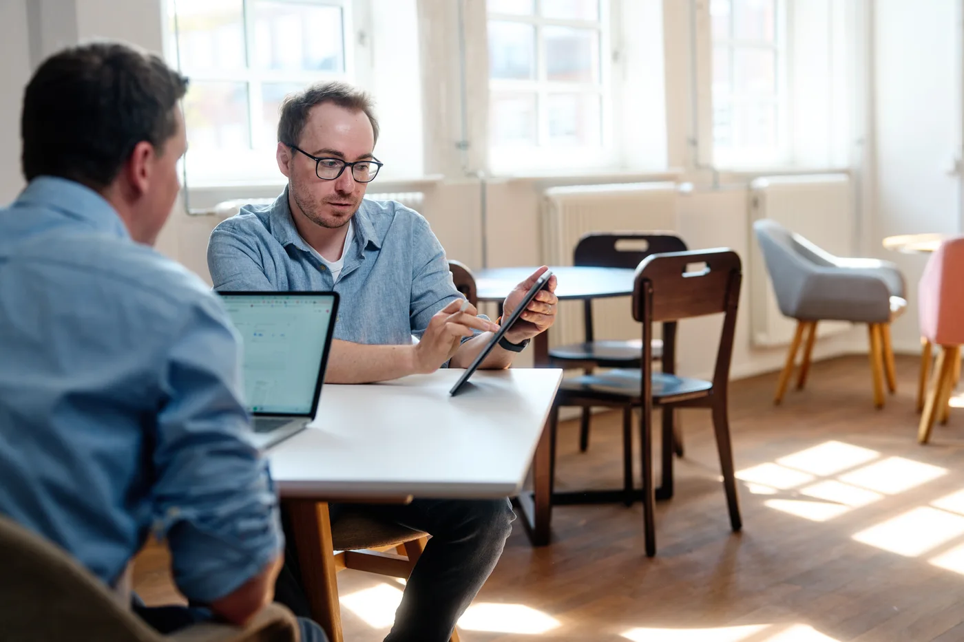 Lennart und Sören am runden Tisch mit Laptop im Agenturbüro