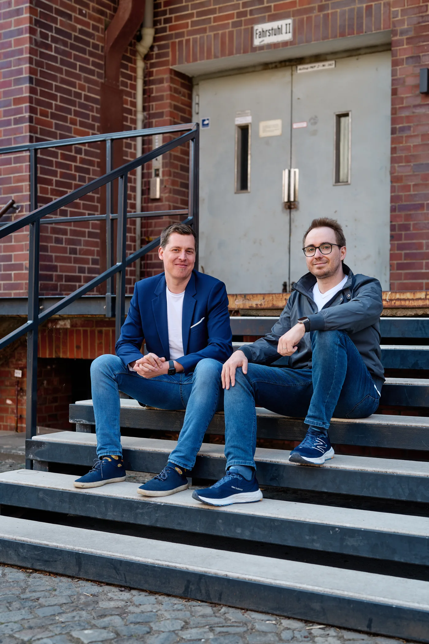 Lennart und Sören sitzen vor dem Gebäude auf einer Treppe